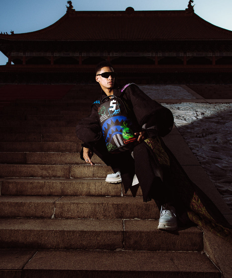 Sprayground - शार्क सेंट्रल एक्स डीएलएक्सएसवी पीठ बैग आउटलेट